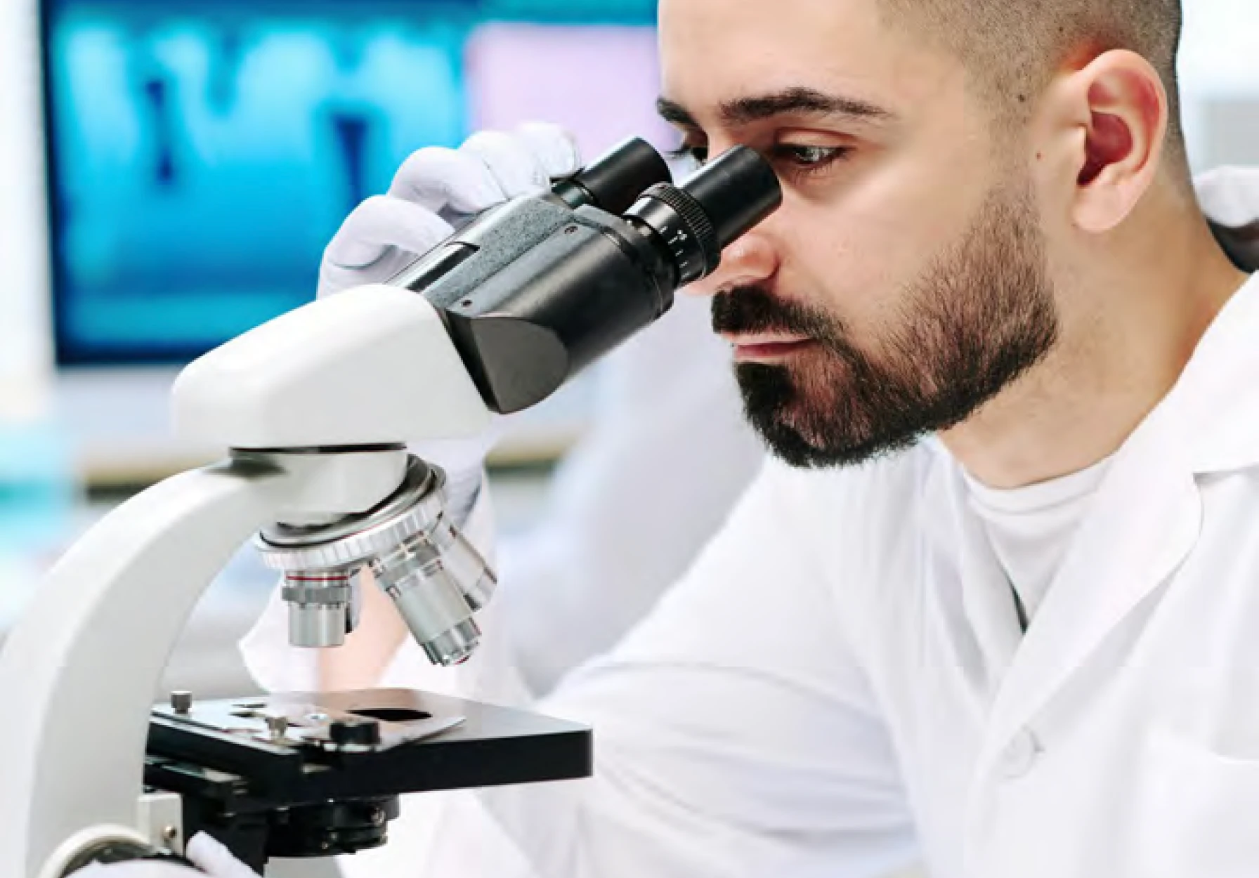 Medical researcher examining samples under microscope in modern lab facility