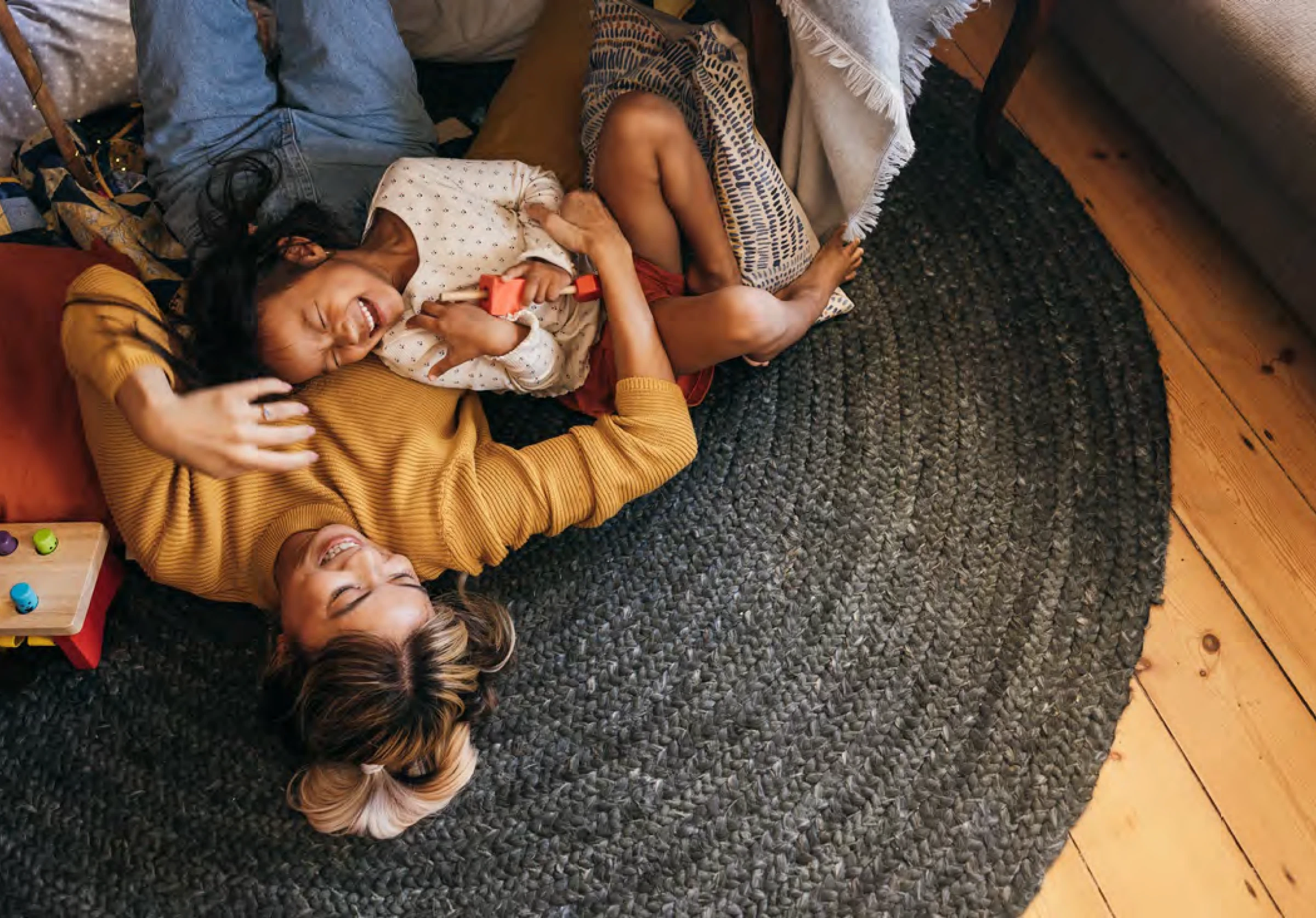 Mother and young child laughing together while playing on cozy living room floor